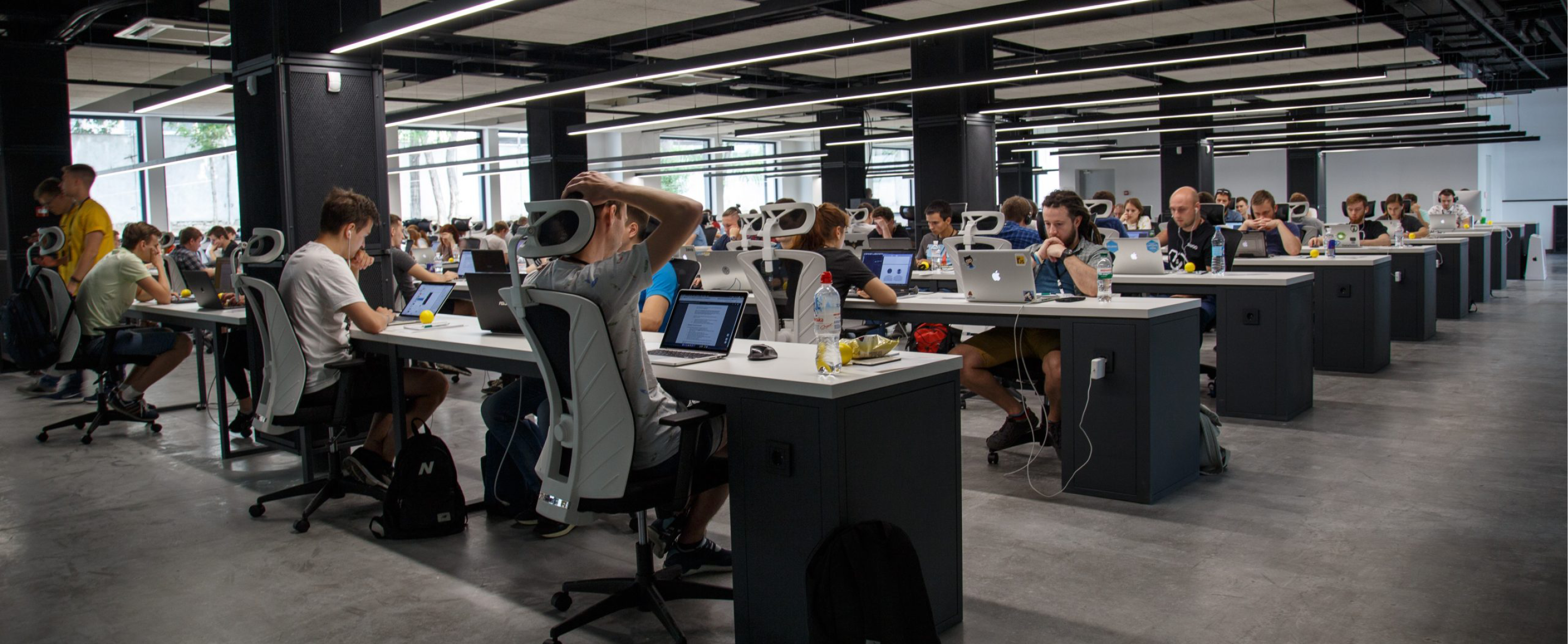 a large open office with dozens of of people working at open desks